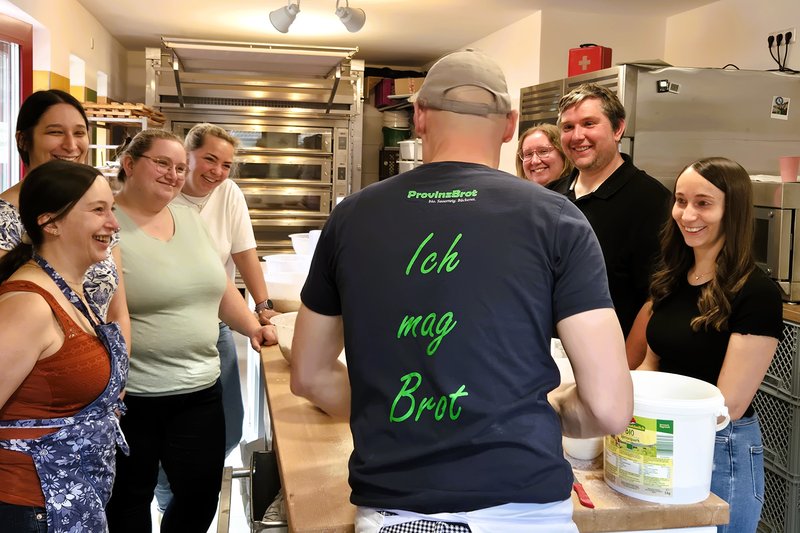 Thomas der Bäckermeister erklärt den Sauerteig Brotbackkurs-TeilnehmerInnen wie der Teig geknetet wird